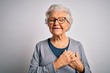 Senior beautiful grey-haired woman wearing casual sweater and glasses over white background smiling with hands on chest with closed eyes and grateful gesture on face. Health concept.