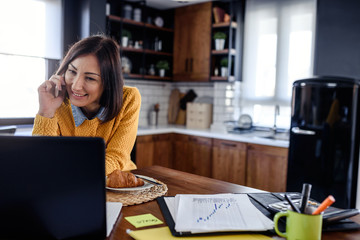 Wall Mural - Young business entrepreneur woman working at home while having breakfast