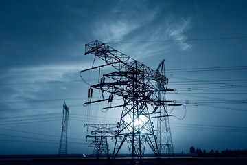 Wall Mural - High voltage towers, silhouetted in the setting sun