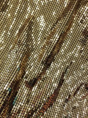 Close up of a fabric decorated with shiny gold sequins