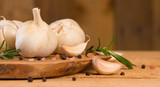 Fototapeta Miasto - Garlic with rosemary and thyme and spices on a wooden background