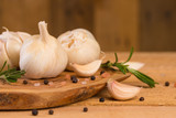 Fototapeta Miasto - Garlic with rosemary and thyme and spices on a wooden background