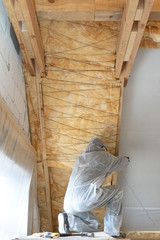 Wall Mural - Foreman in overalls working with rockwool insulation material