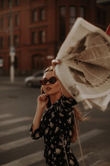 Girl with a newspaper on a city street.