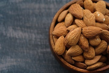 Wall Mural - Almonds nuts close-up in a wooden spoon on a wooden brown scratched background.Raw almonds in a round wooden cup  .Vegetarian and vegan food.Healthy food.