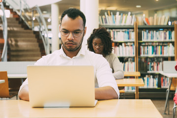 Wall Mural - focused adult students working in public library computer class. people sitting at desks and using l