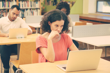 Wall Mural - adult students working on computer during class. multiethnic man and women sitting at desk and using