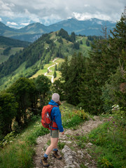 woman with backpack hiking in forested mountains enjoying the scenic view