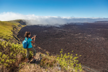 galapagos tourist hiking on volcano sierra negra on isabela island taking photos with camera. woman 