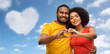 © Syda Productions - love, valentines day and people concept - happy african american couple making hand heart gesture over blue sky and clouds background