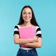 © FreepikCompany - Smiling woman holding stack of books