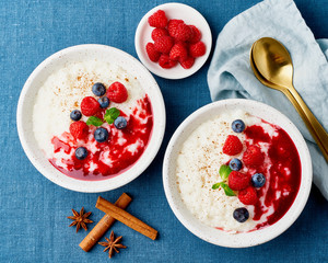 Wall Mural - Rice pudding. French milk rice dessert with raspberries, blueberries. Blue linen textile. Top view