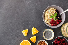 Food And Breakfast Concept - Oatmeal Cereals In Bowl With Wild Berries, Fruits, Almond Nuts And Poppy Seeds On Slate Stone Table