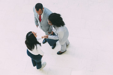 Diverse partners welcoming each other in office hallway. Business man and women standing and shaking hands. Business meeting concept