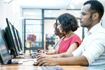 Wall Mural - mix raced adult students training in computer class. row of man and women in casual sitting at table