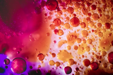 macro close-up photo of sparkling purple orange carbonated water in bright lit clear oil creating a 