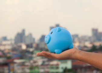 Piggy bank, laying on hand, investment model, saving money, backdrop, city, village.