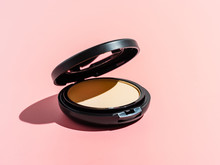 Compact Powder On Pink Background. Female Pressed Powder In Ajar Opened Black Plastic Case With Mirror, Copy Space For Text Or Design. Hard Light