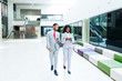 © Mangostar - Diverse business professionals consulting internet on mobile phones. Business man and woman walking through office hallway and using smartphones. Wireless communication concept