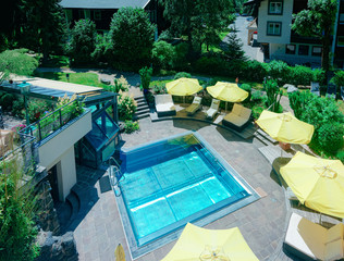 Modern swimming pool with yellow umbrellas at green background