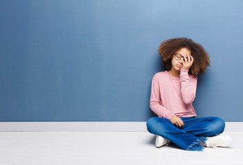 Wall Mural - african american little girl looking unhappy and stressed, suicide gesture making gun sign with hand, pointing to head sitting on the floor