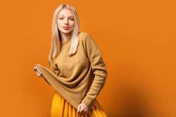 Wall Mural - Young woman in warm sweater on color background