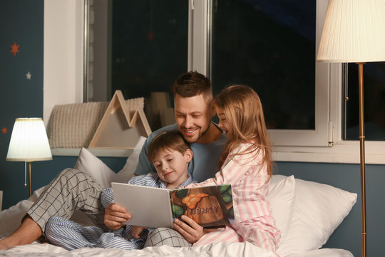 father and his little children reading bedtime story at home