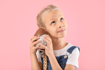 Sticker - Cute little girl with sweet chocolate egg on color background