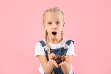 Sticker - Surprised little girl with sweet chocolate eggs on color background