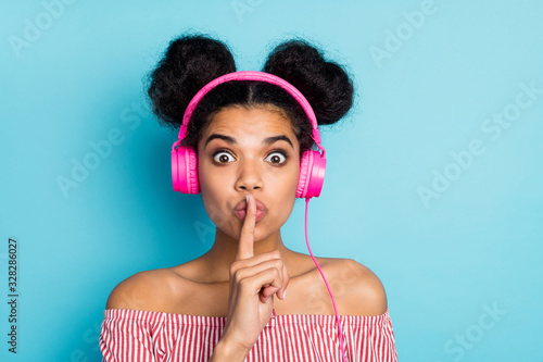 Shh. My favorite song. Closeup photo of funny dark skin lady listen music modern earphones hold finger on lips wear red white striped shirt off-shoulders isolated blue color background
