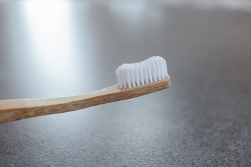 Closeup of a wooden toothbrush. Bamboo biodegradable eco toothbrush against a gray background with copy space. Plastic free concept.  Place for text