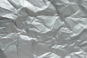 Crumpled silver matte foil texture. Abstract gray wrinkled sheet pattern, top view