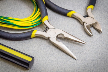 Two pliers tool and wires for an electrician on dark background are used by the master to repair electricity