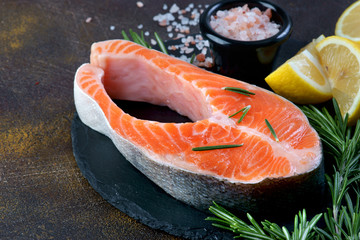 salmon steak on a dark background with lemon and spices