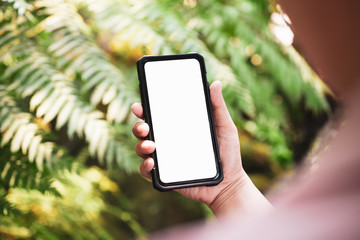 mockup image of a person holding white blank screen smart phone with blur green nature background. m