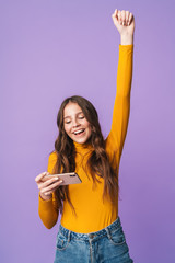 Wall Mural - Image of young beautiful woman rejoicing and holding cellphone