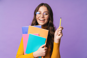 Image of young beautiful student girl smiling and holding exercise books