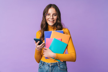 Wall Mural - Image of young student girl holding exercise books and cellphone