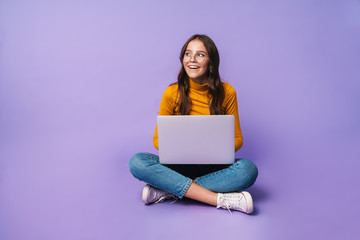 image of young woman using laptop while sitting with legs crossed