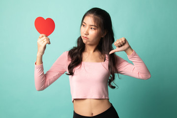 Asian woman thumbs down with red heart.