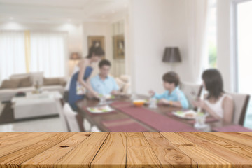 Beautiful pattern of empty brown plank wooden board as mock-up display shelf or counter with blurred background activity of four peoples as dad-mom-son-daughter have breakfast in a cozy dining room.