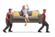 © Ljupco Smokovski - Woman sitting on a sofa and pointing up while two workers from a removal company carry the sofa