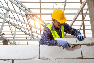 bricklayer builder working with autoclaved aerated concrete blocks. Walling, installing bricks on construction site, Engineering and constructions concepts.