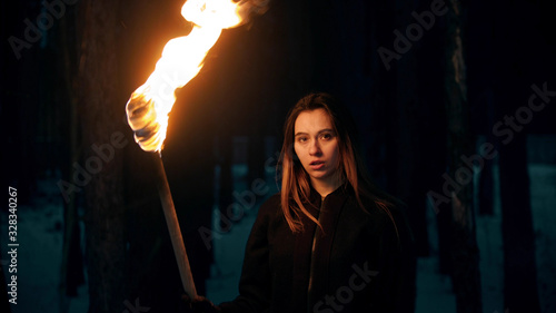 Fotomural Young woman with torch posing in night forest