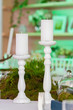 2 large white candles on white wooden cones stand on the table as part of table decoration, decor