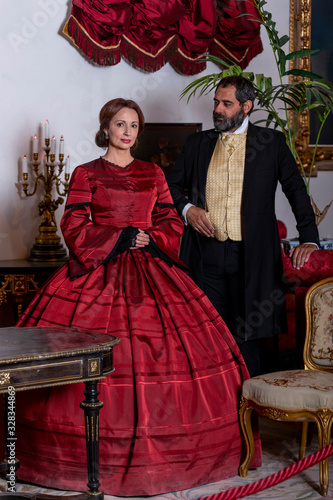 Photographie A woman and a man, elegantly dressed, in 19th-century-style clothes, pose standi