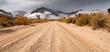 Low perspective of dirt road in mojave desert california with snow capped mountains in the background
