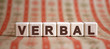 Verbal word on wooden cubes on a color background