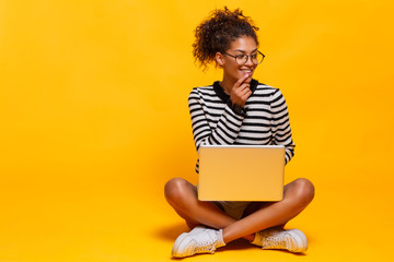 Smiling african woman using laptop computer while sitting looking aside. Copy space. Not isolated.