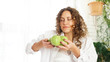 © brillianata - Beautiful young woman with curly hair smelling green apples
